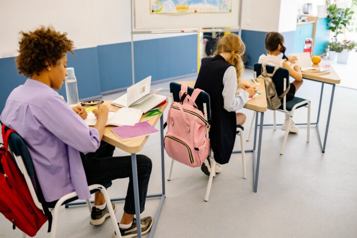 Studenti in classe con libri e zaini a scuola