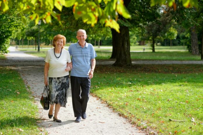 Anziani invecchiamento attivo. Coppia di anziani cammina mano nella mano in un parco.