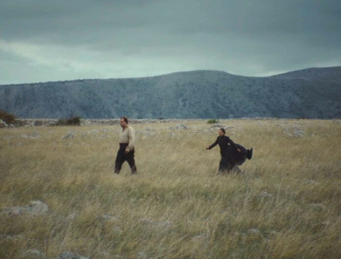 Terra del Fuoco: un uomo e una donna attraversano un prato, fotogramma del film di Hana Jušić