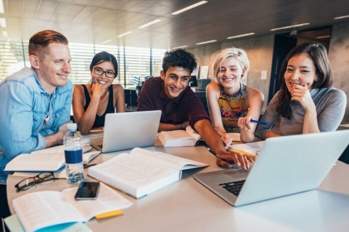 Giovani Qualità del lavoro. Giovani professionisti collaborano a un progetto davanti a un computer portatile in un ufficio.