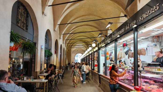 Tavolini Sotto il Salone, interno del mercato storico di Padova con botteghe e volte medievali.