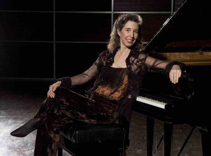 Stagione OPV: Angela Hewitt seduta accanto a un pianoforte a coda