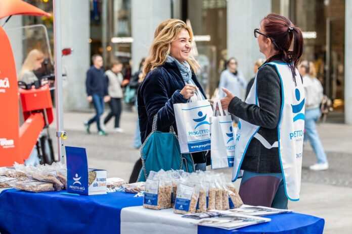 Zuppa della Bontà, una volontaria di Progetto Arca consegna una confezione al banchetto