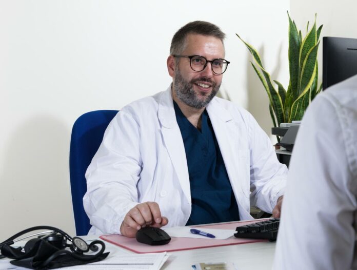 Enrico Peterle in camice bianco alla scrivania del suo ambulatorio