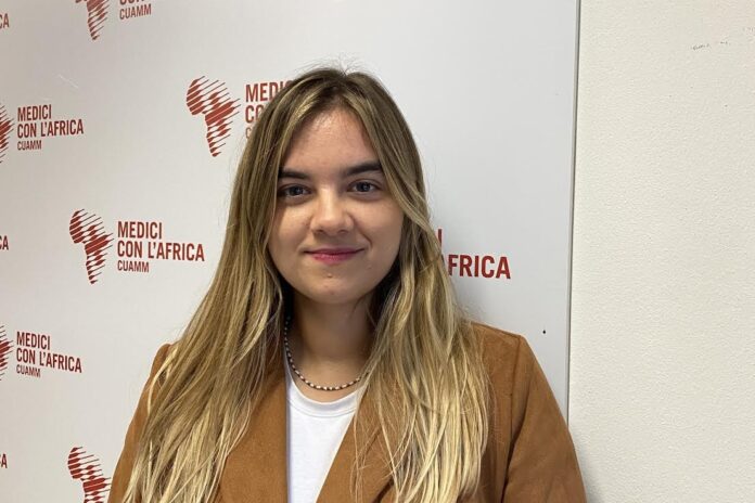 Anna Cipriano davanti al logo di Medici con l’Africa Cuamm prima della partenza per l’Etiopia